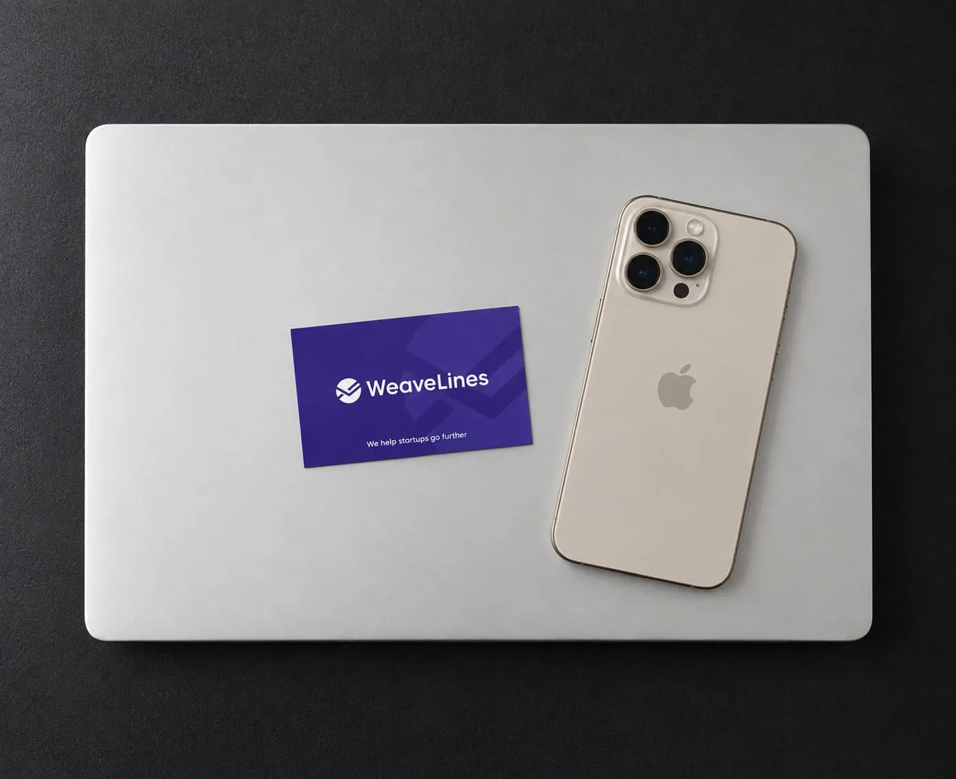A WeaveLines business card and a phone lying on a closed laptop.
