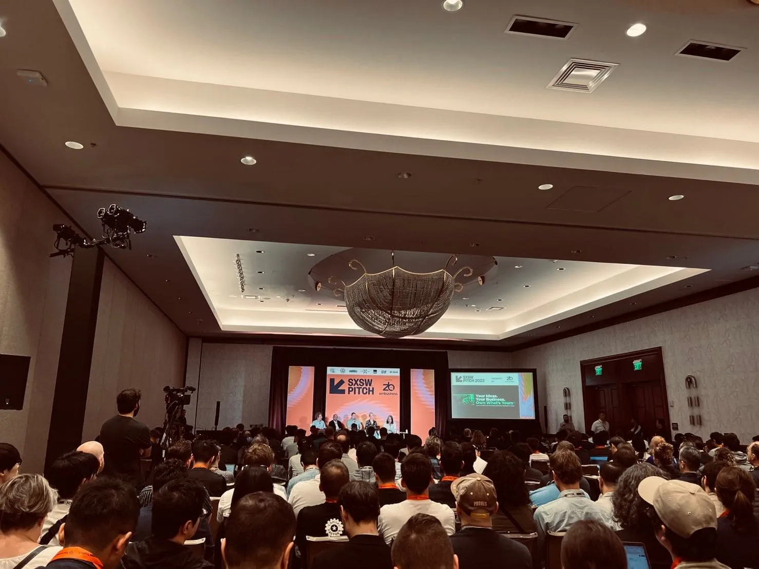 A full conference hall seen from the back rows, a panel on stage under a SXSW Pitch banner.