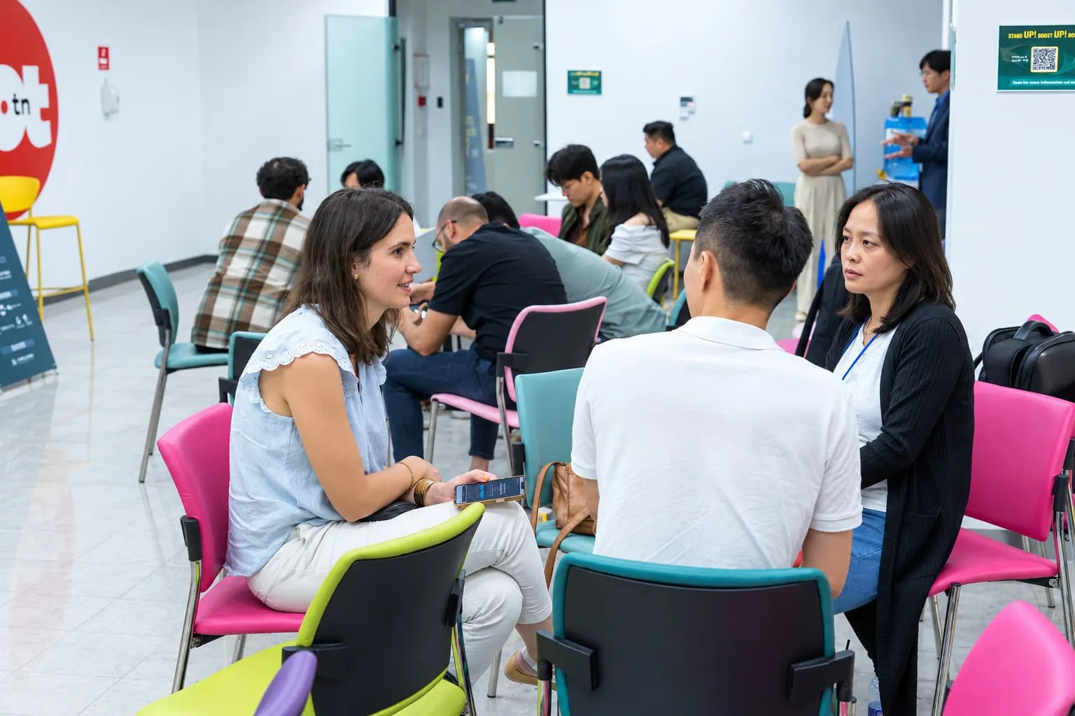 A room of people in low chairs, turned towards each other in conversation.